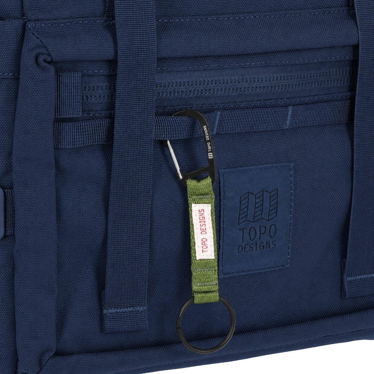 General detail Shot of the Topo Designs Rover Pack Tech in "Navy" showing key clip attached to front daisy chain webbing.