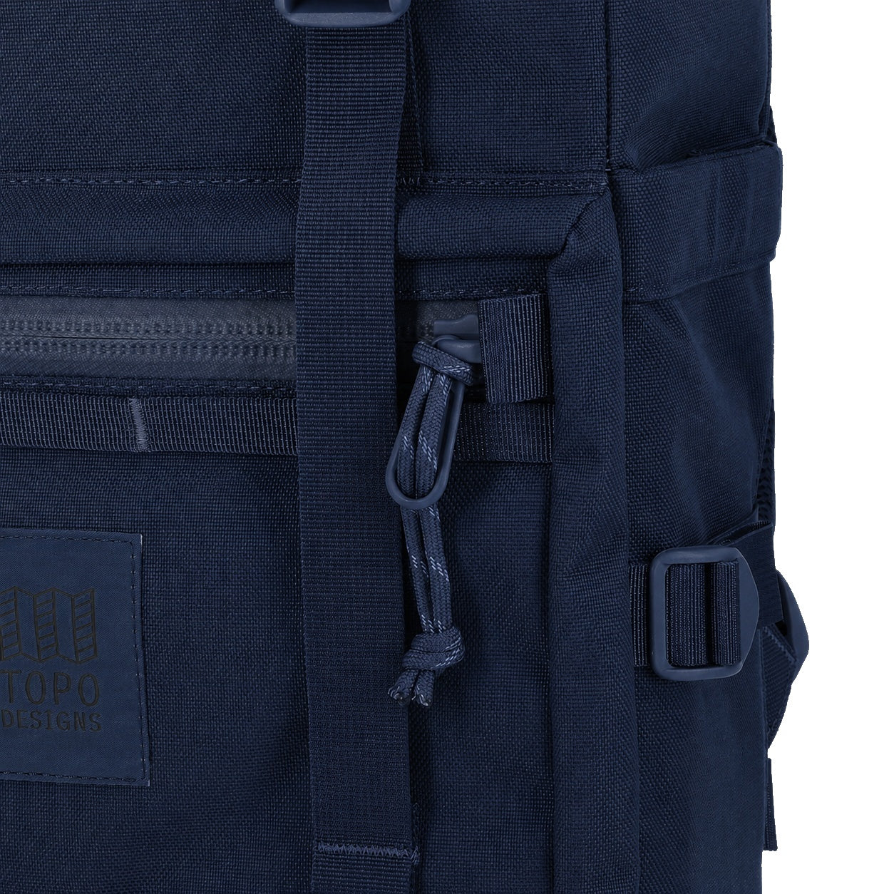 General detail Shot of the Topo Designs Rover Pack Tech in "Navy" showing front logo patch, zipper pulls, and daisy chain webbing.